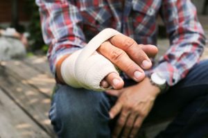 A man in a checked shirt has a bandaged hand.