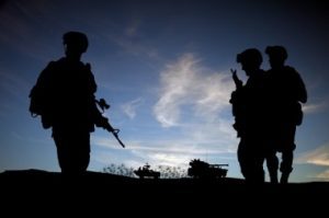 Silhouettes of three army soldiers at night.