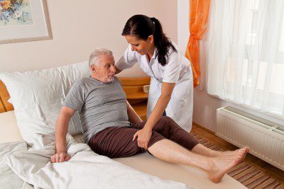 A care home nurse helping a resident get back into bed to avoid care home negligence