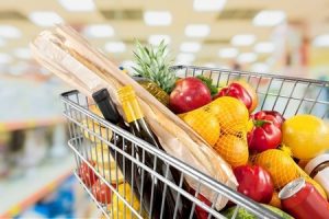 a shopping trolley containing fruits and vegetables, bread and two wine bottles