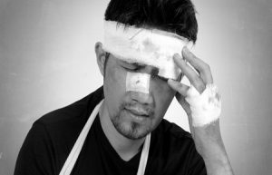 Injured man covered in bandages holds head in discomfort