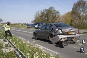 A car in the middle of the road with a destroyed car boot.