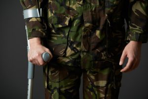 A torso shot of an army soldier in camouflage with crutches.