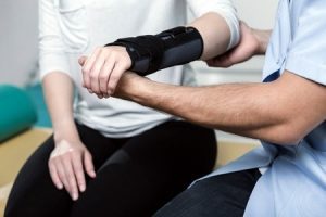 A doctor holding a woman's bandaged arm., who may wish to learn about carpal tunnel surgery claims