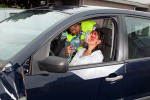 A woman in a car who has facial injuries.