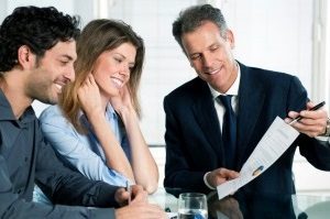 A solicitor smiling showing a document to a couple.