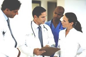 A group of doctors discuss a patient's injuries.