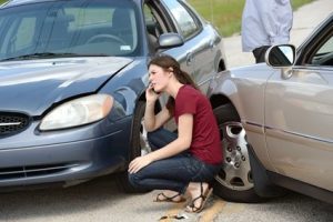 A woman knelt beside two cards after a T-bone collison.