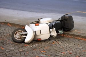 A white moped laying on its side in the road.