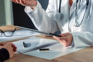 A doctor holding a medical chart talking with a patient