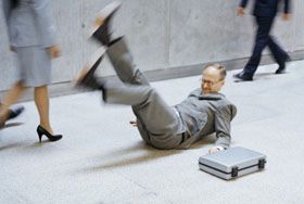 A man in a grey suit on the ground having slipped and fell in his office building