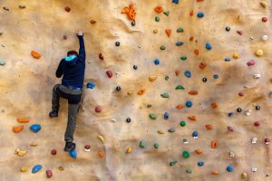 A man ascends a climbing wall.