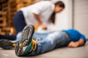 A worker lay on the ground, with a woman knelt beside him checking whether he is okay