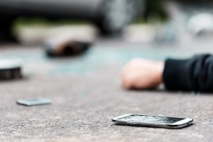 A broken discarded phone on the road after a pedestrian was hit by a car.