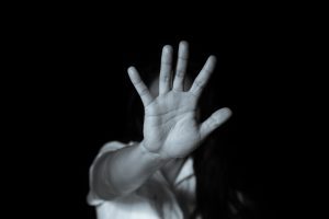 A black and white picture of a person holding their hand up and turning their head away