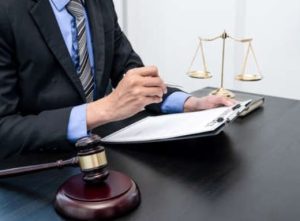 A solicitor sat at a desk with a judge's gavel and justice scales reviewing documents from criminal injury claims