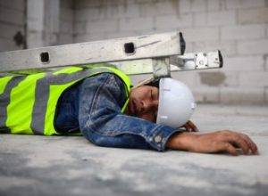 Injured worker lying on the floor with collapsed ladder on top of them.