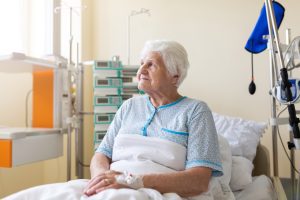 An elderly lady in a care home bed looking out of the window.