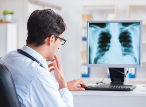 A doctor looks at a patient's scan displayed on his computer, afraid of GP negligence claims.