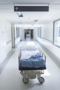 An empty hospital bed in an empty corridor.