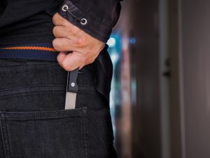 A man placing a knife into his back pocket after stabbing
