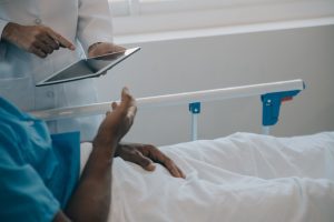 A doctor is showing a patient in a hospital bed some content on a tablet. 