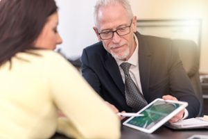 A solicitor showing his client documents on a tablet while discussing breast cancer negligence claims