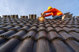 A builder fixing a roof on a council house 
