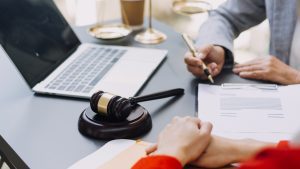 A person asking their solicitor, "can patients claim for falling out of bed in hospital?" with a gavel hammer on the desk and set of justice scales in the background