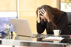 A woman sits with her head in her hands after a data breach.