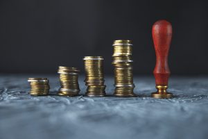 Piles of coins and a stamp press representing a compensation claim against a landlord or agent 