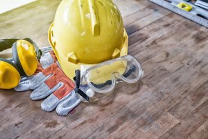 PPE gear featuring a yellow hard hat, safety goggles, yellow and black ear protectors, and gloves.