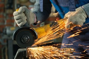 Sparks fly from a welding saw while being used by a worker.