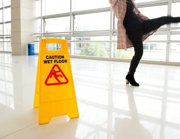 a woman slipping over a wet floor in a public place