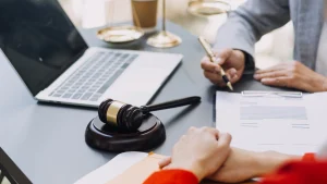 A seated solicitor takes notes for a client navigating the foreign object in food claims process