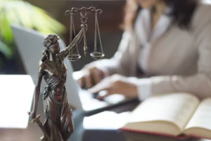 A medical negligence solicitor works at a desk on their laptop with a Lady Justice statue in the foreground